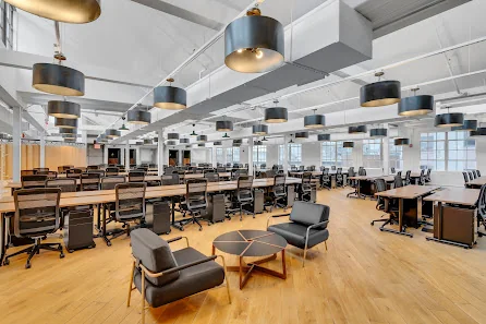 The Mark Manhattan Laundry massive open-plan coworking floor with rows of desks, large drum pendant lights, and hardwood floors