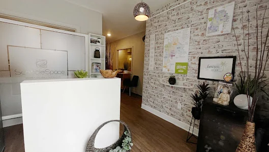 ScribbleSpace LLC cozy boutique reception with white counter, distressed brick wallpaper, bulletin board, and plants