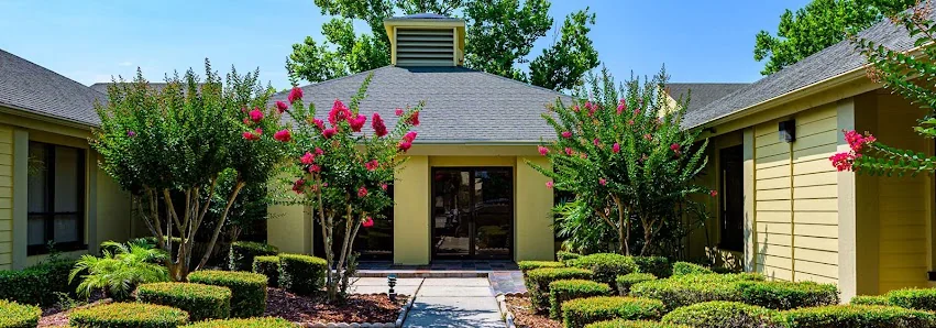 Corner Suites Coworking single-story olive building with landscaped entrance walkway, pink crepe myrtle trees, and manicured hedges