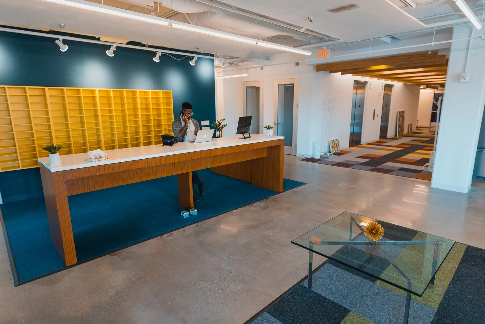 The Yard Eastern Market reception with teal wall, yellow mail cubbies, colorful floor tiles and glass table